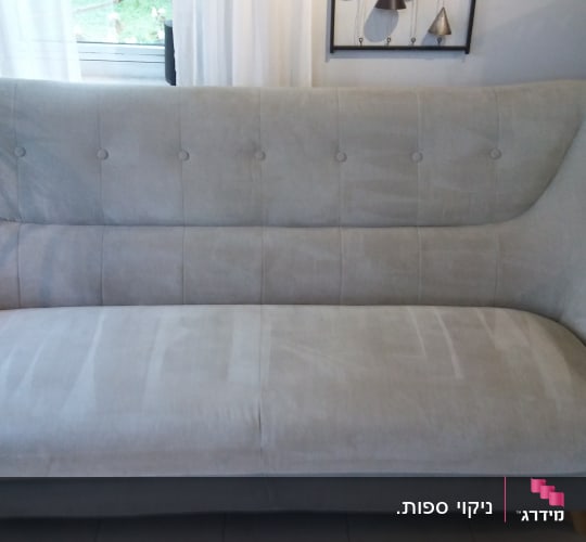 ספה אפורה עם כפתורים על משענת הגב